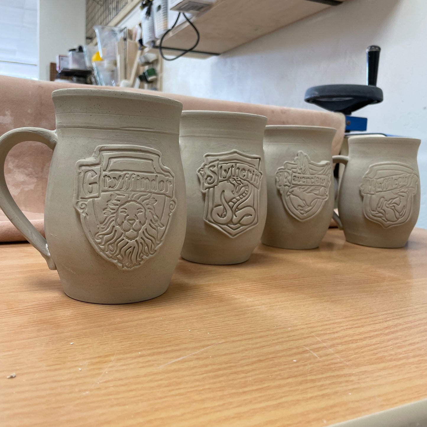 Harry Potter Hogwarts ceramic mugs in process. Bone Dry stage, ready for first firing.