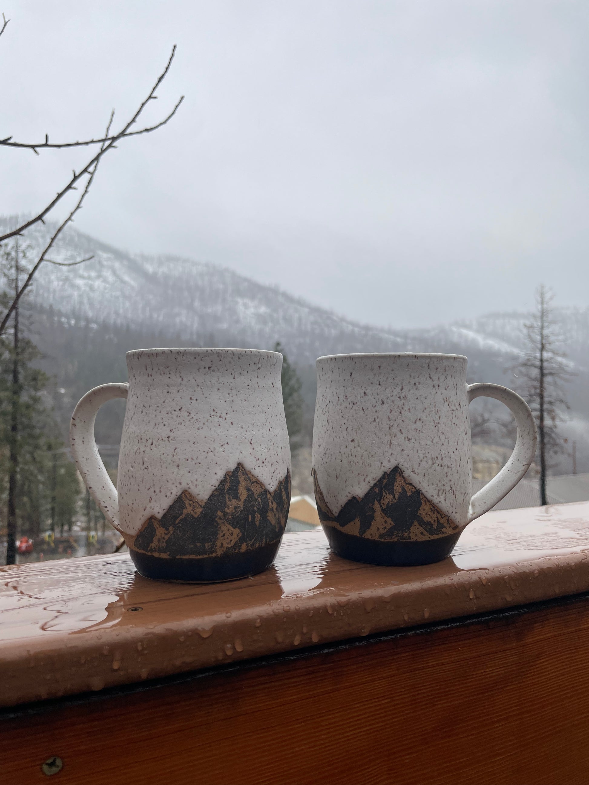 a Set of Nature coffee mugs featuring a mountain range over a glossy blue glaze representing a lake or ocean.